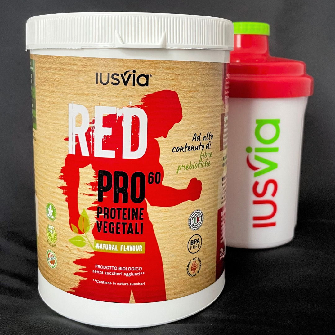 Prodotto RED PRO 60 Proteine vegetali Natural Flavour Ad alto contenuto di fibre proteiche. Nello sfondo si vedo lo shake IUSVIA.