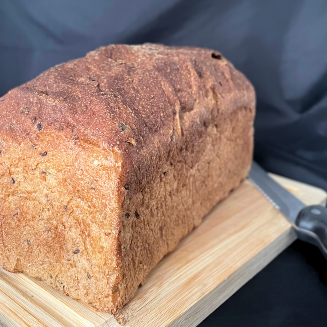 Foto prodotto Pane Fermentato Proteico da Agricoltura Biologica. Si vede il pane intero sopra un tagliere di legno e il coltello per tagliare il pane.